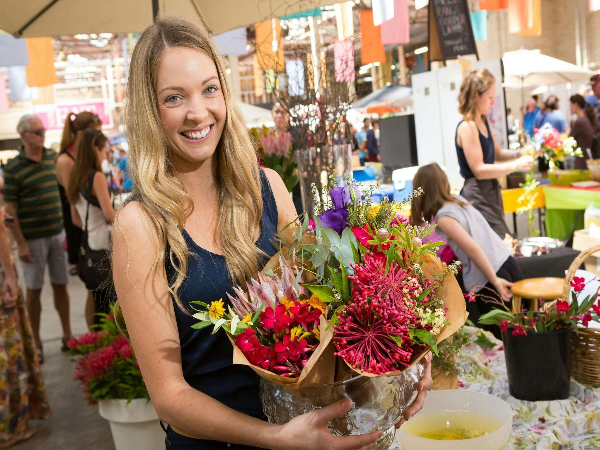 Bunches of fresh native flowers being held by a visitor at the Old Bus Depot Markets