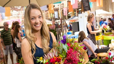 Bunches of fresh native flowers being held by a visitor at the Old Bus Depot Markets