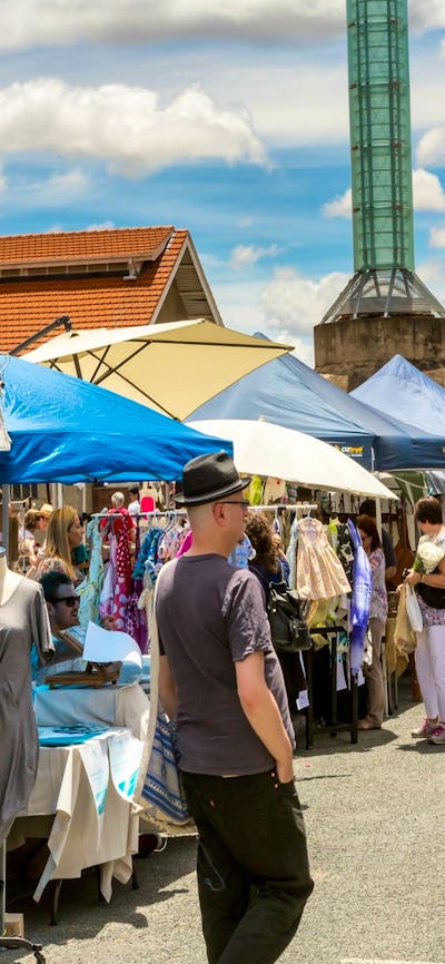 Outdoor stalls and visitors at the front of the Old Bus Depot Markets