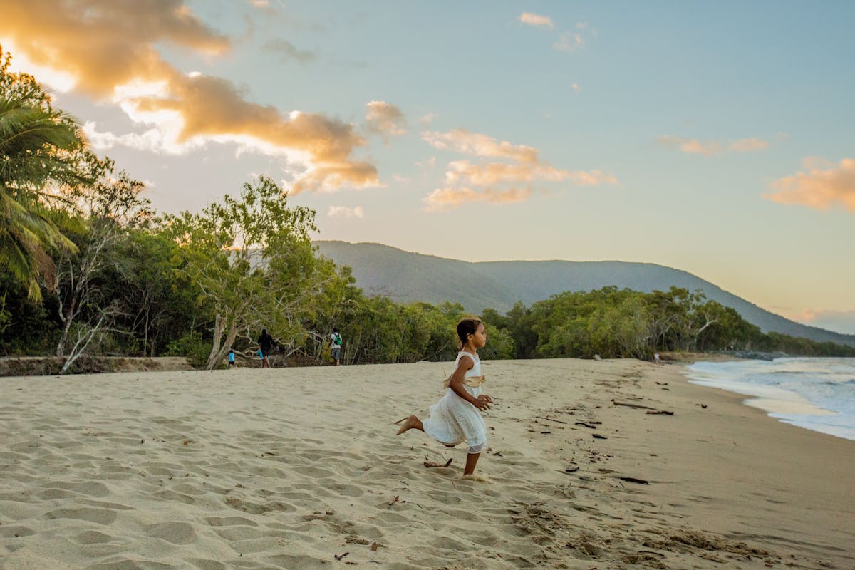 Girl running along Kewarra beach at sunset