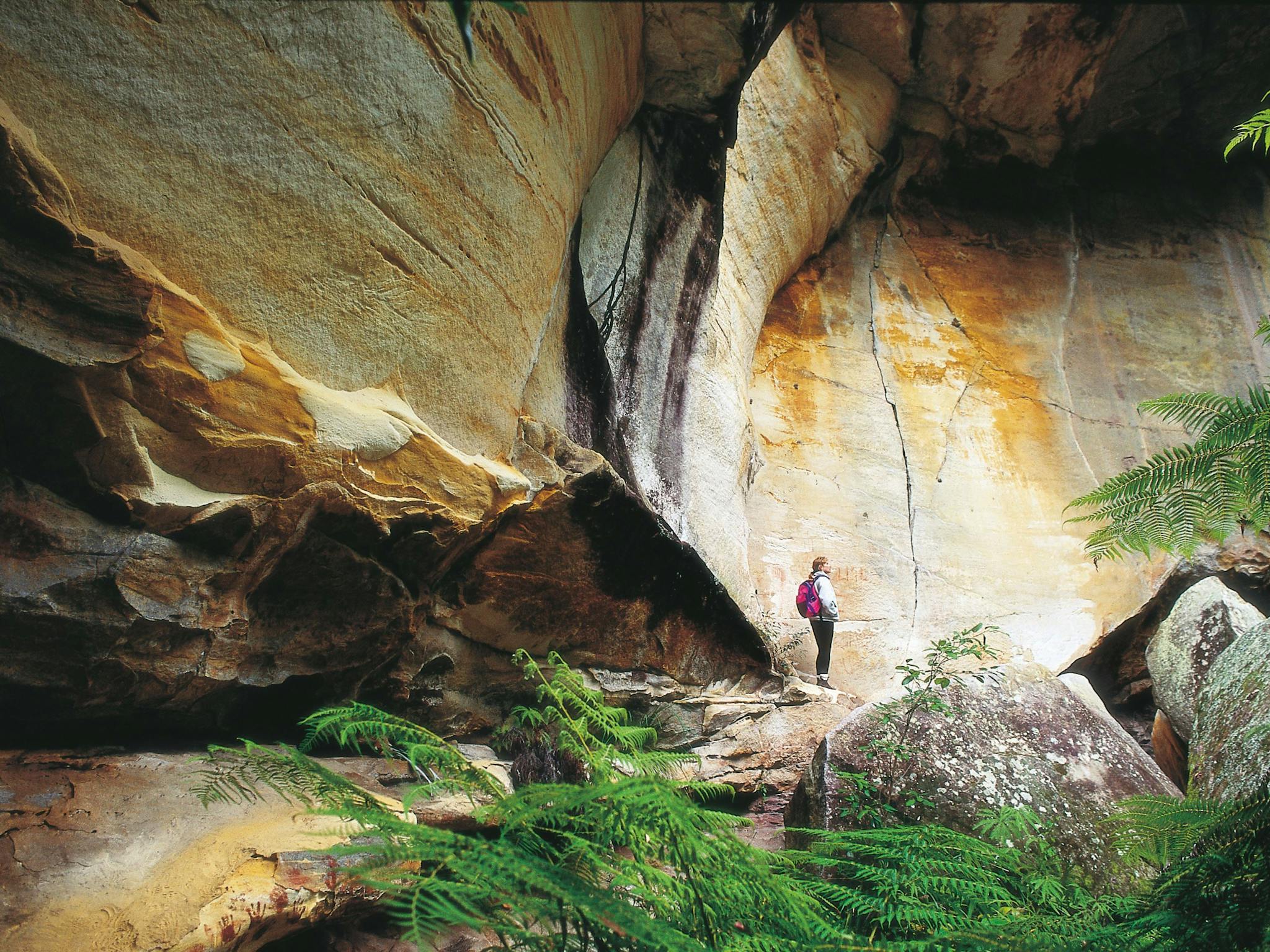 Person standing near sandstone cliff face in Cania Gorge National Park Person standing near sandstone cliff face in Cania Gorge National Park