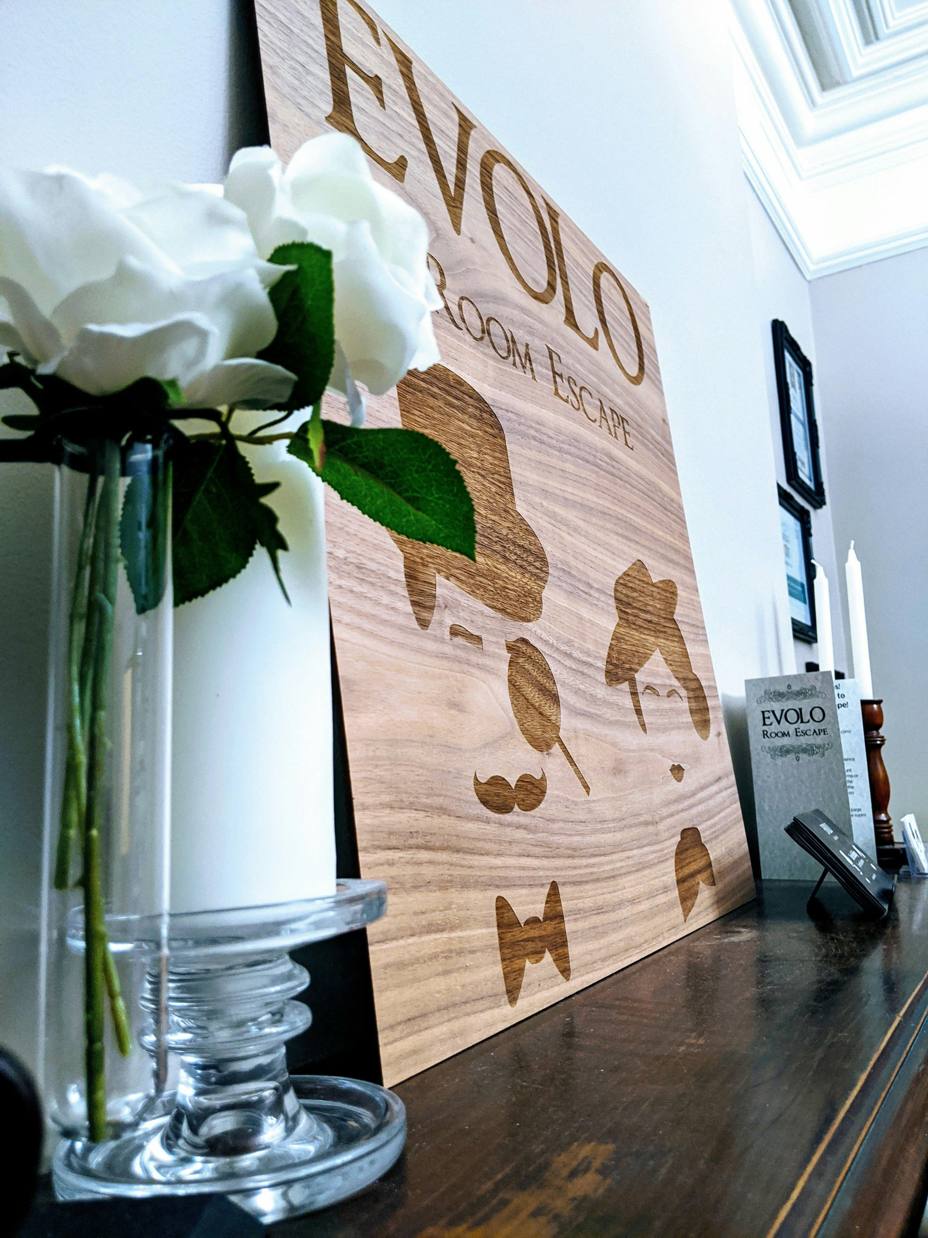 Evolo Room Escape logo board sitting on a mantle with gift vouchers and candle