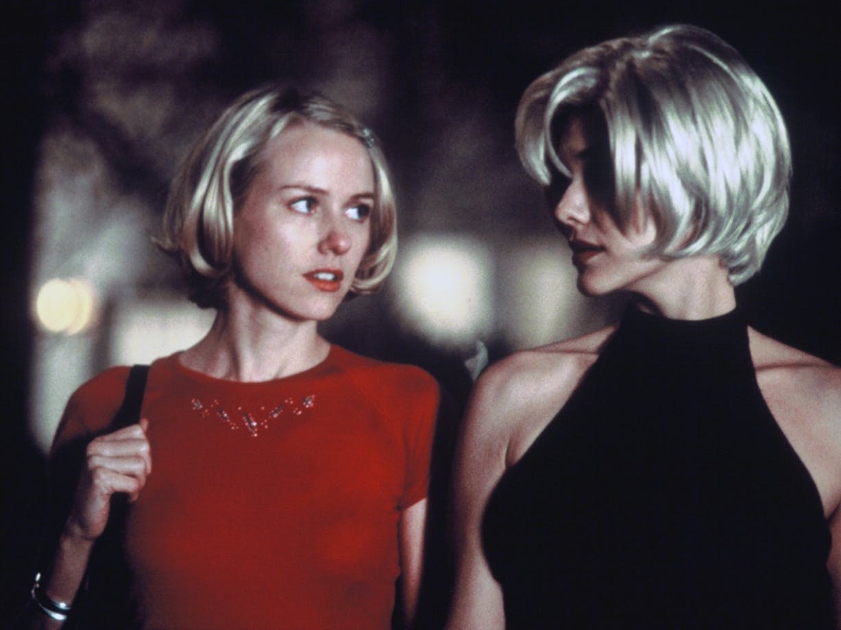 Two women with short blonde hair talking and walking