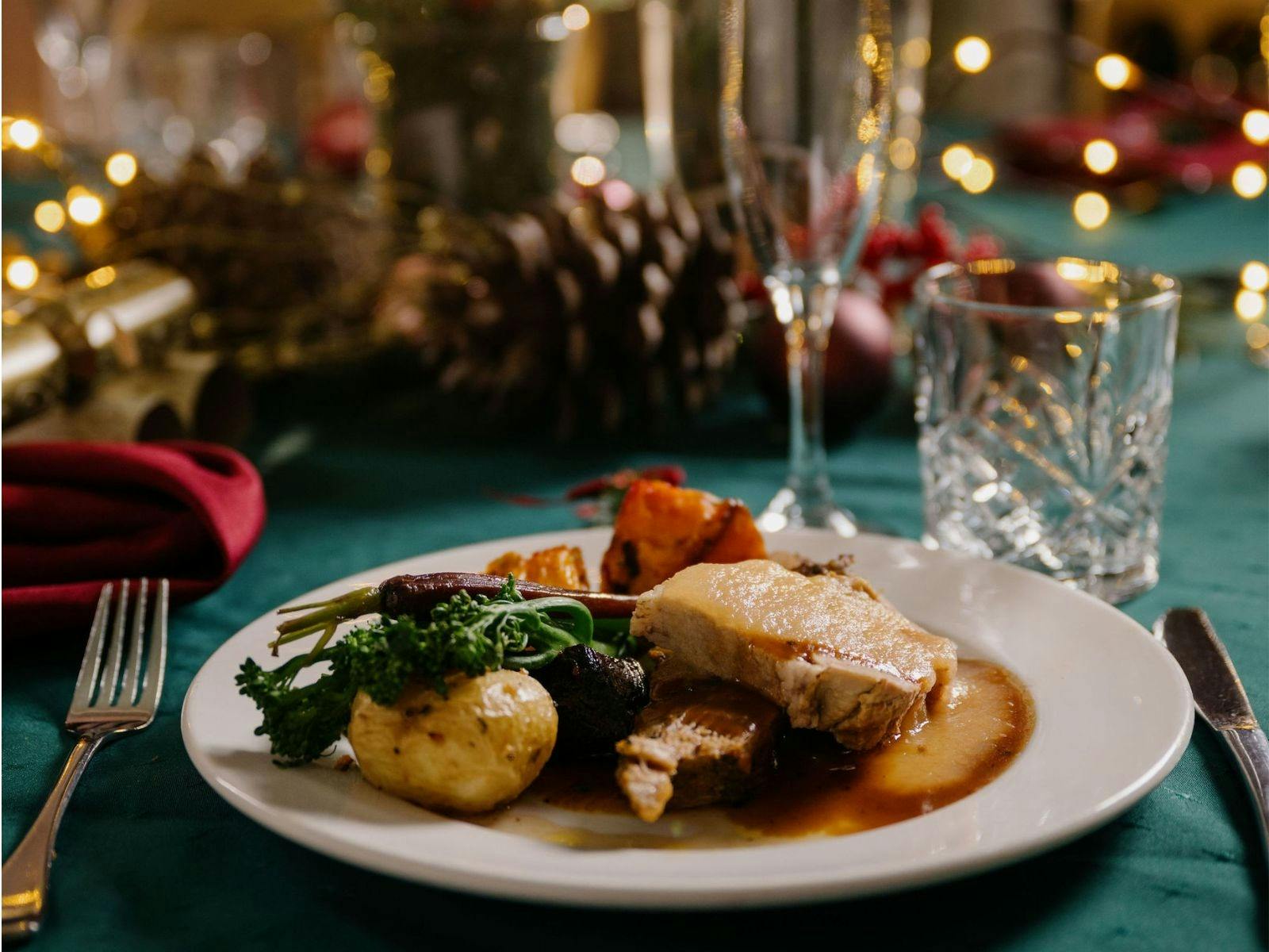 Roast meal with tablewear and Christmas table decorations in the background.
