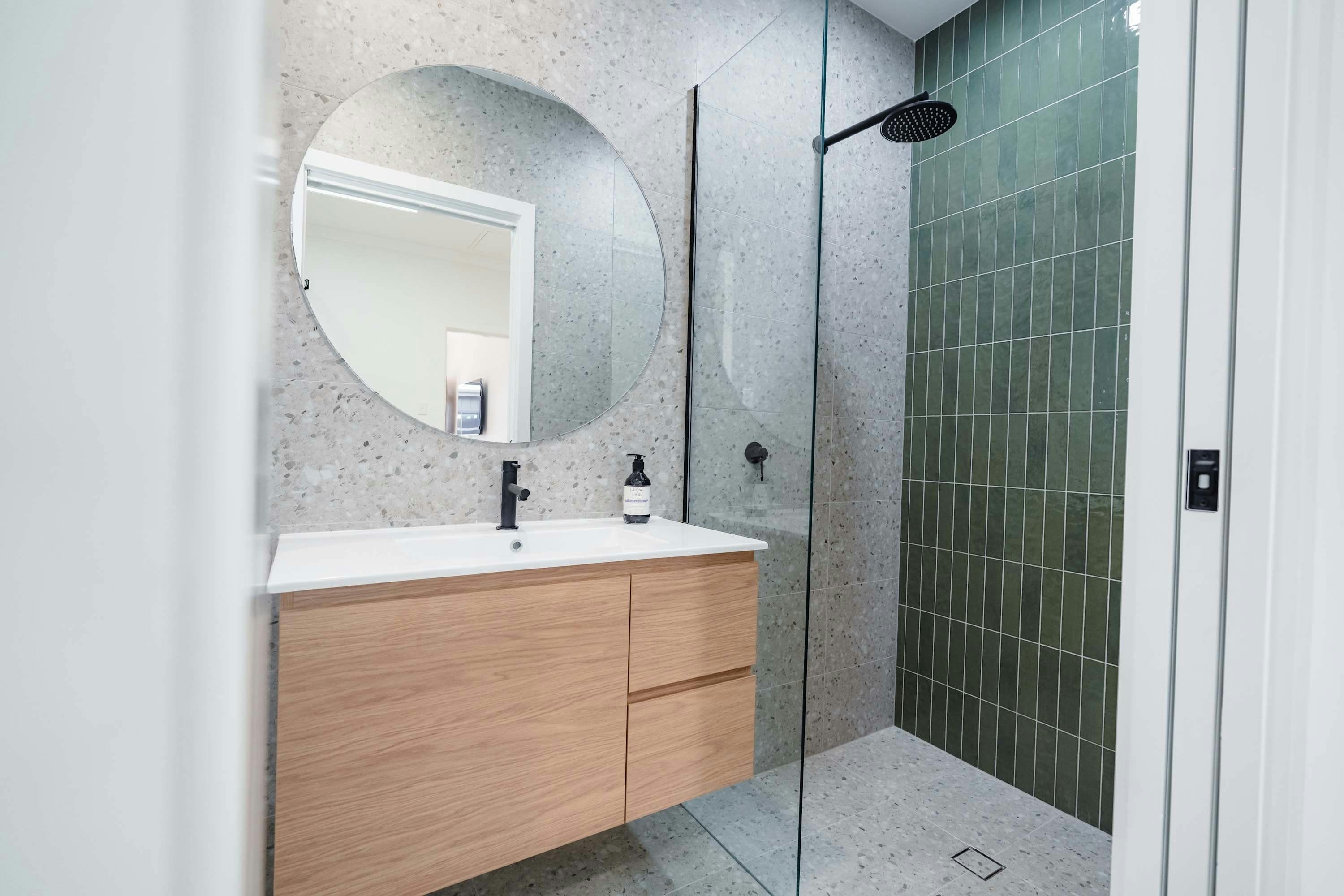 Ensuite with shower, wooden vanity and large circle mirror