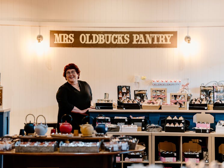 Carol standing under sign in the shop that says "Mrs Oldbucks Pantry"