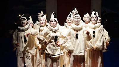group of 12 young people dressed as clowns in all white with black pompoms and white make-up