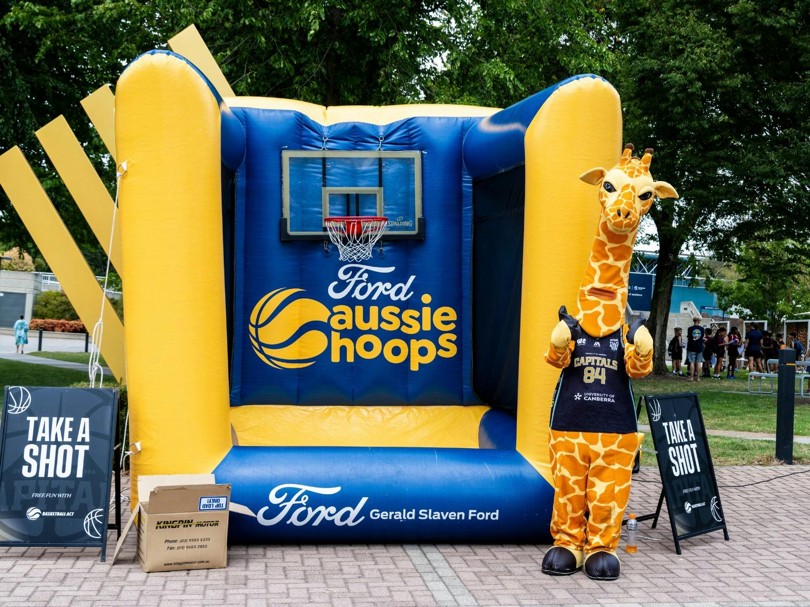 Giraffe mascot in front of a jumping castle.