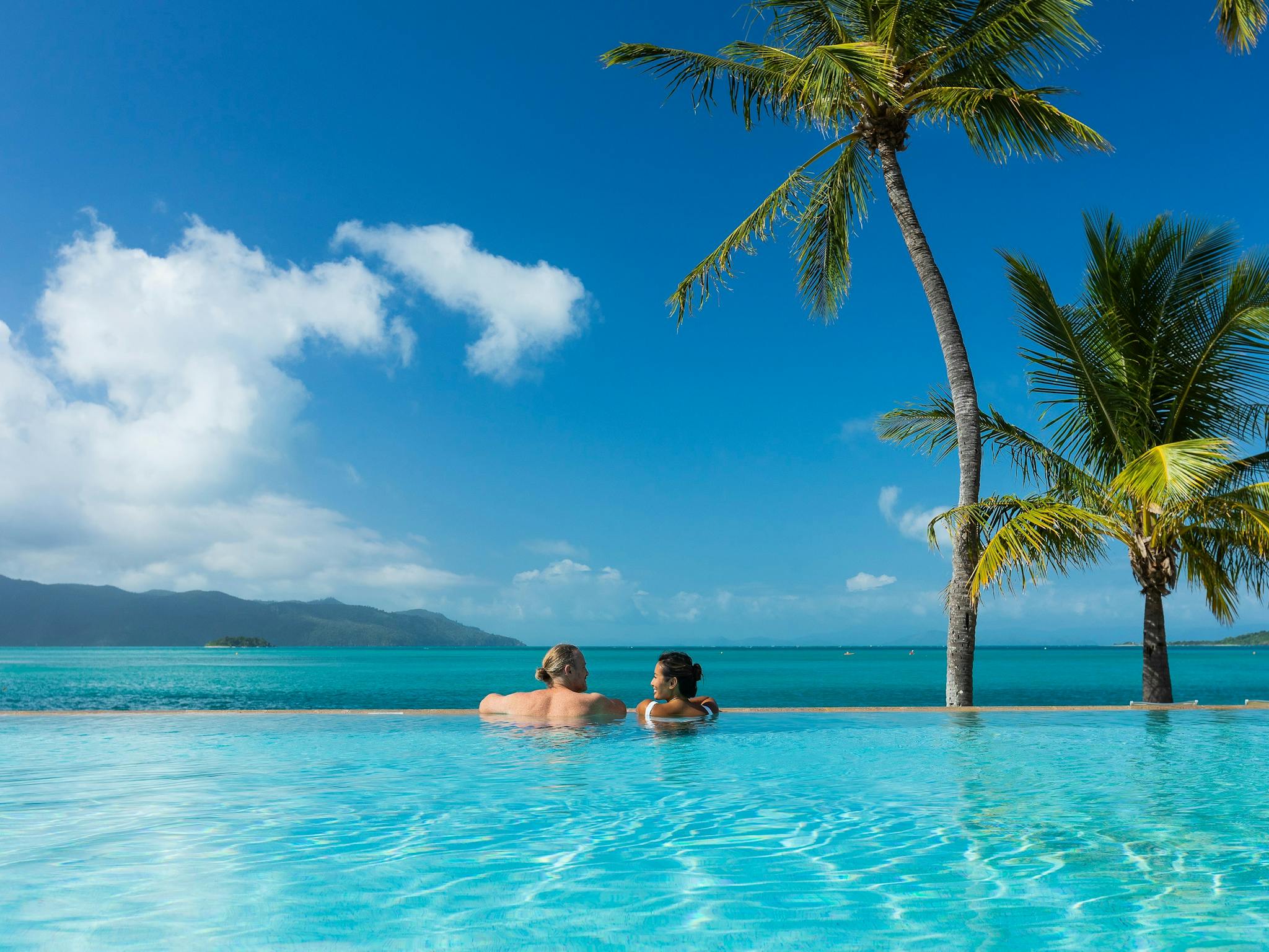 A couple enjoying the ocean views from an infinity pool