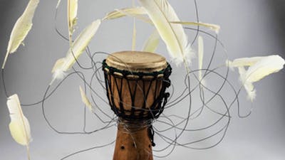 Brown African drum with white feathers which have been attached with wire