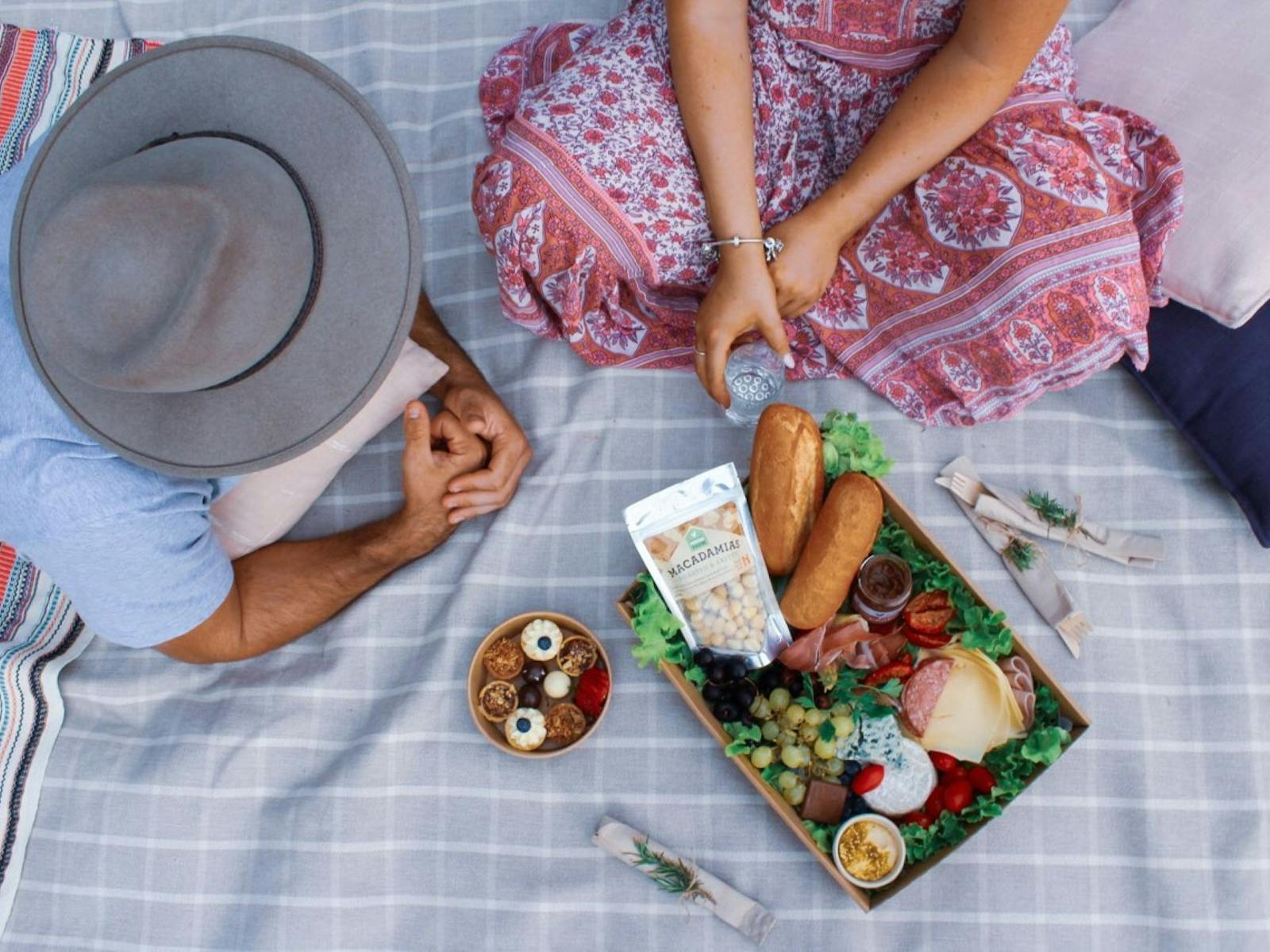 Aerial shot of a couple sitting on a picnic rug with a picnic of farm fresh produce