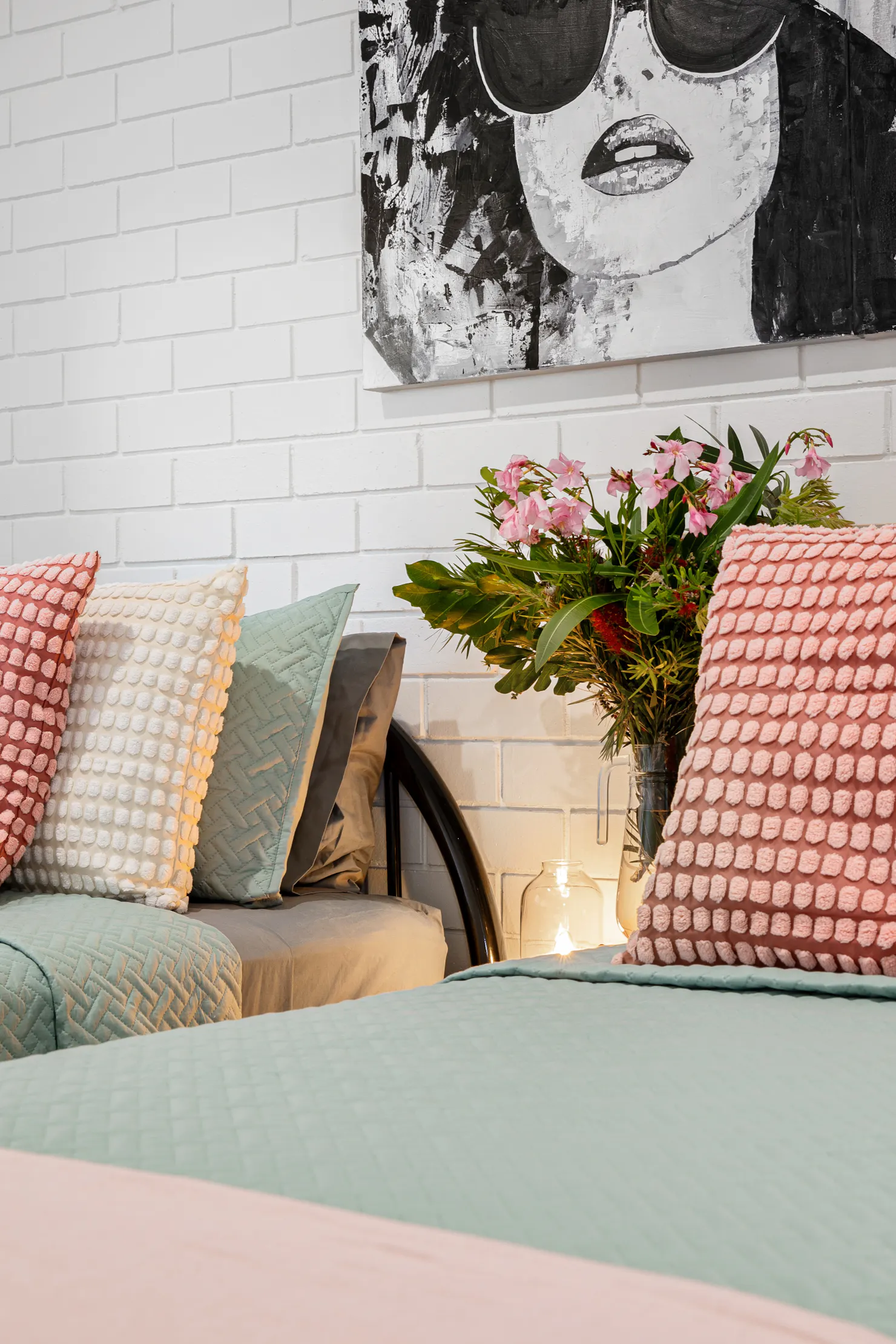 close up of two single beds with pink and green cushions