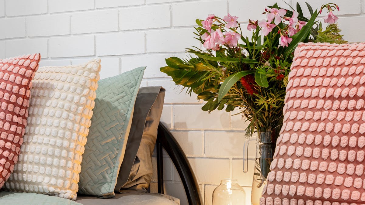 close up of two single beds with pink and green cushions