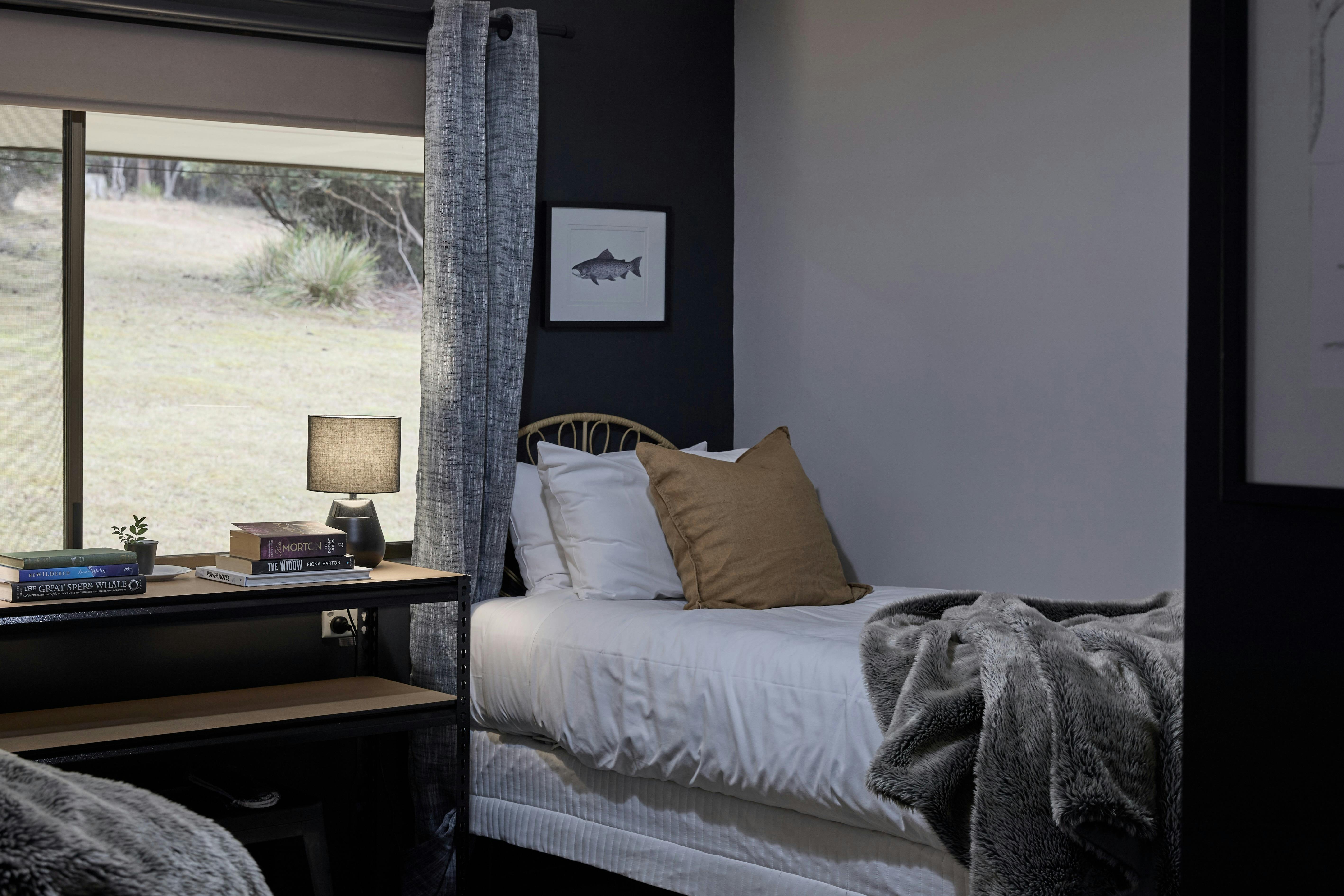 2 single beds in warm earthy and white tones with large window overlooking bush setting