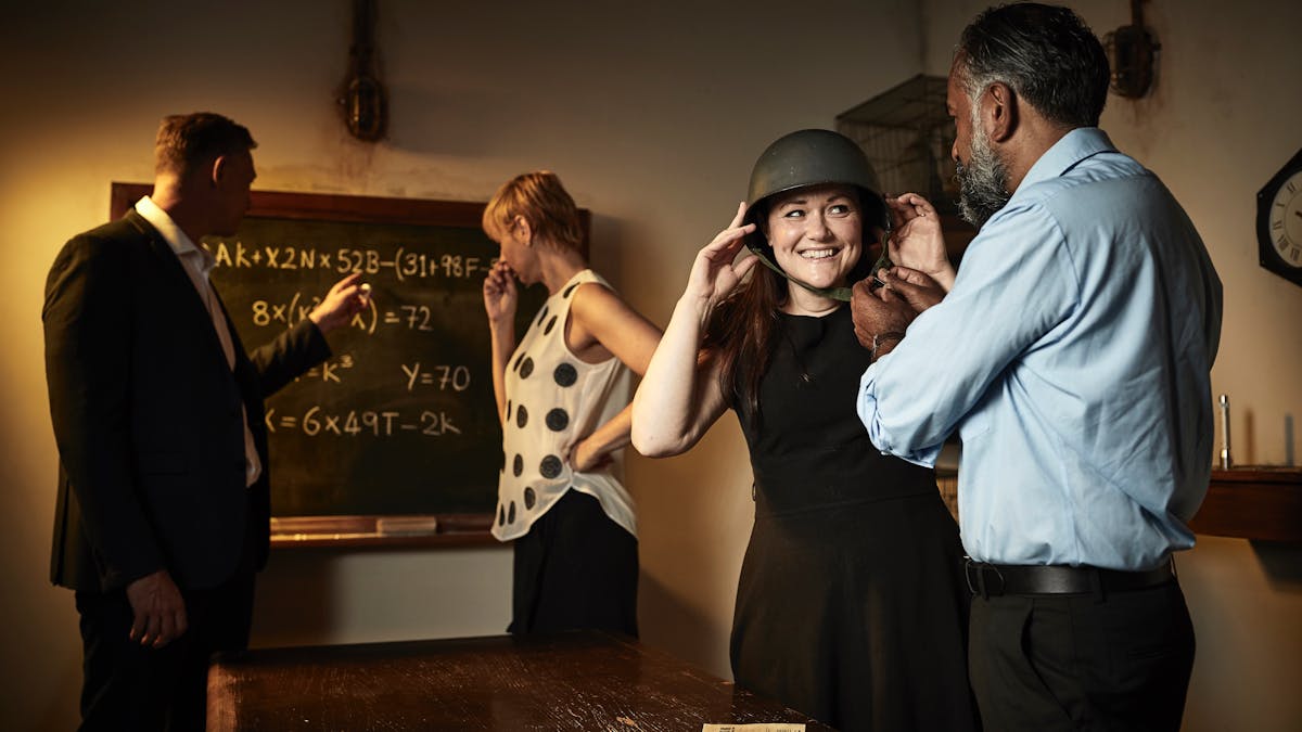Group of 4 happily looking for clues in a world war 2 themed escape room