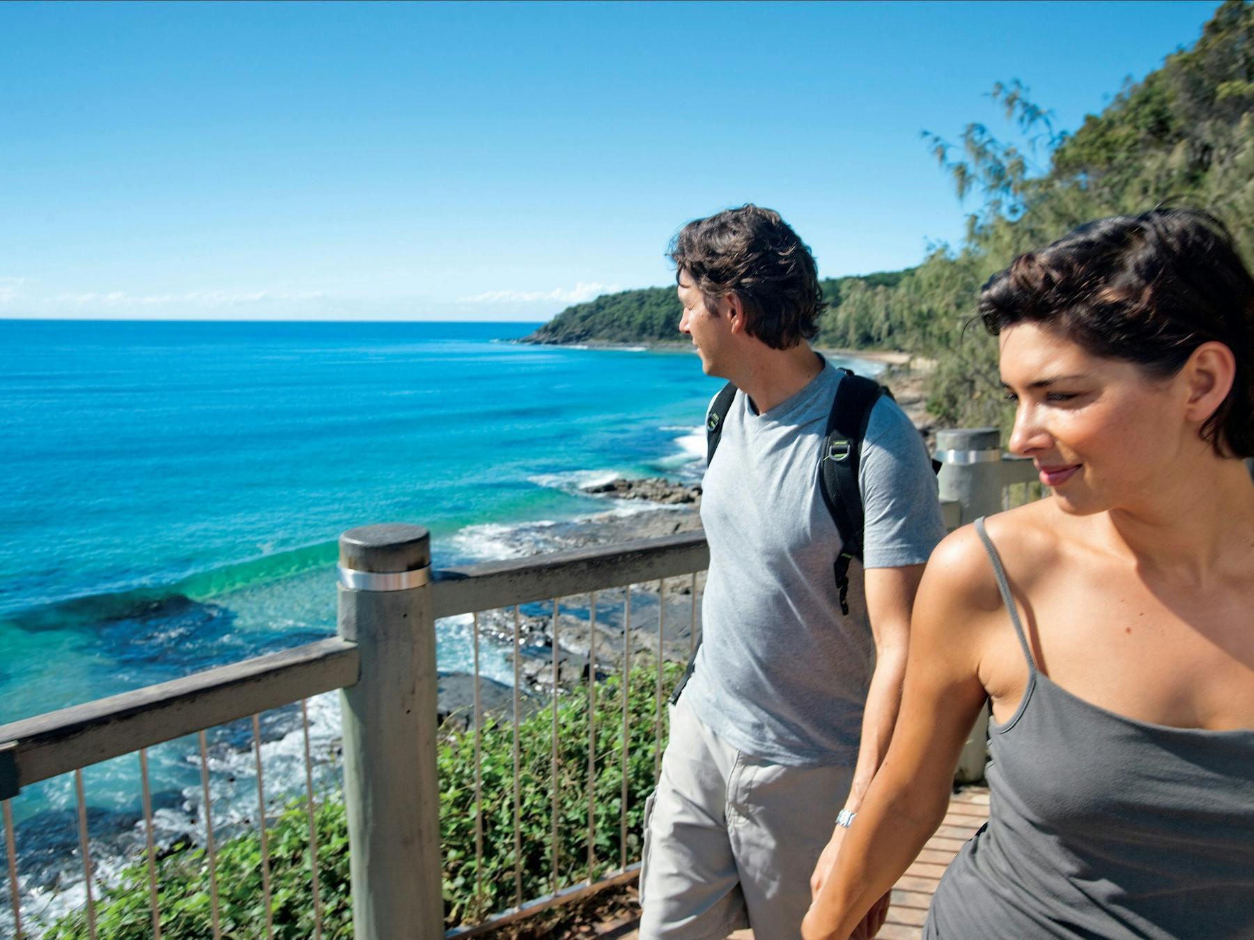 Couple walking along boardwalk on coast.