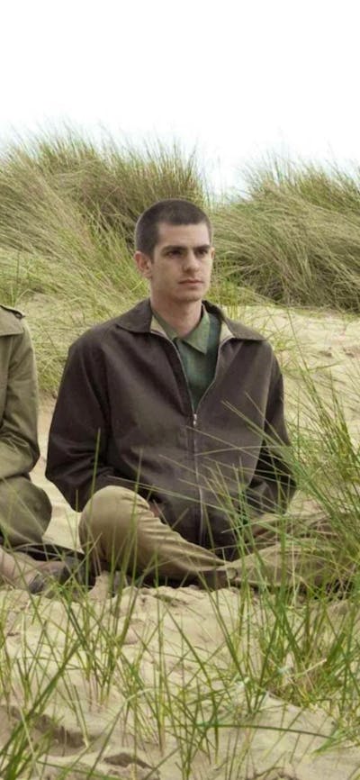 One woman and one man sitting rugged up in coats on a beach