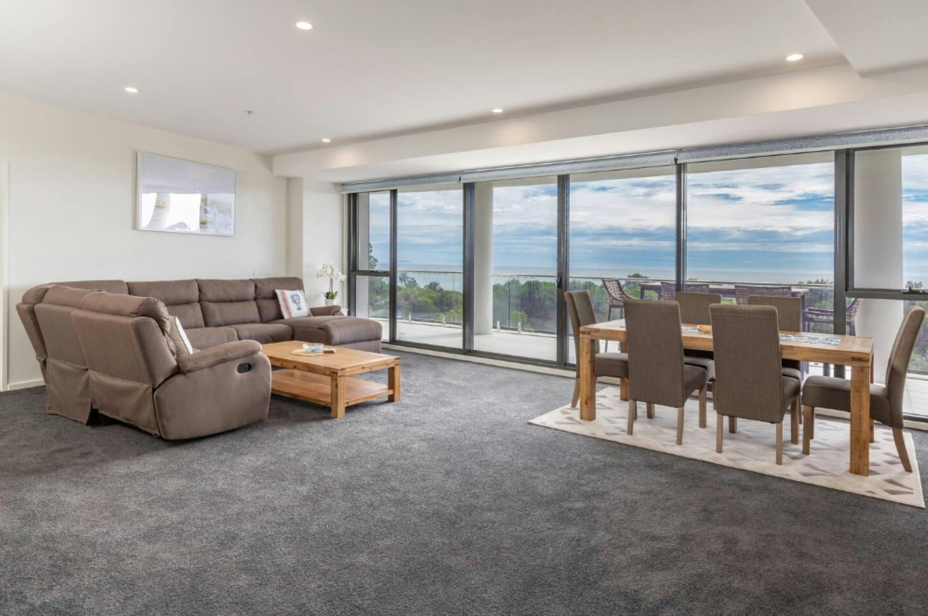 Living area with recliner lounges, dining setting and ocean views