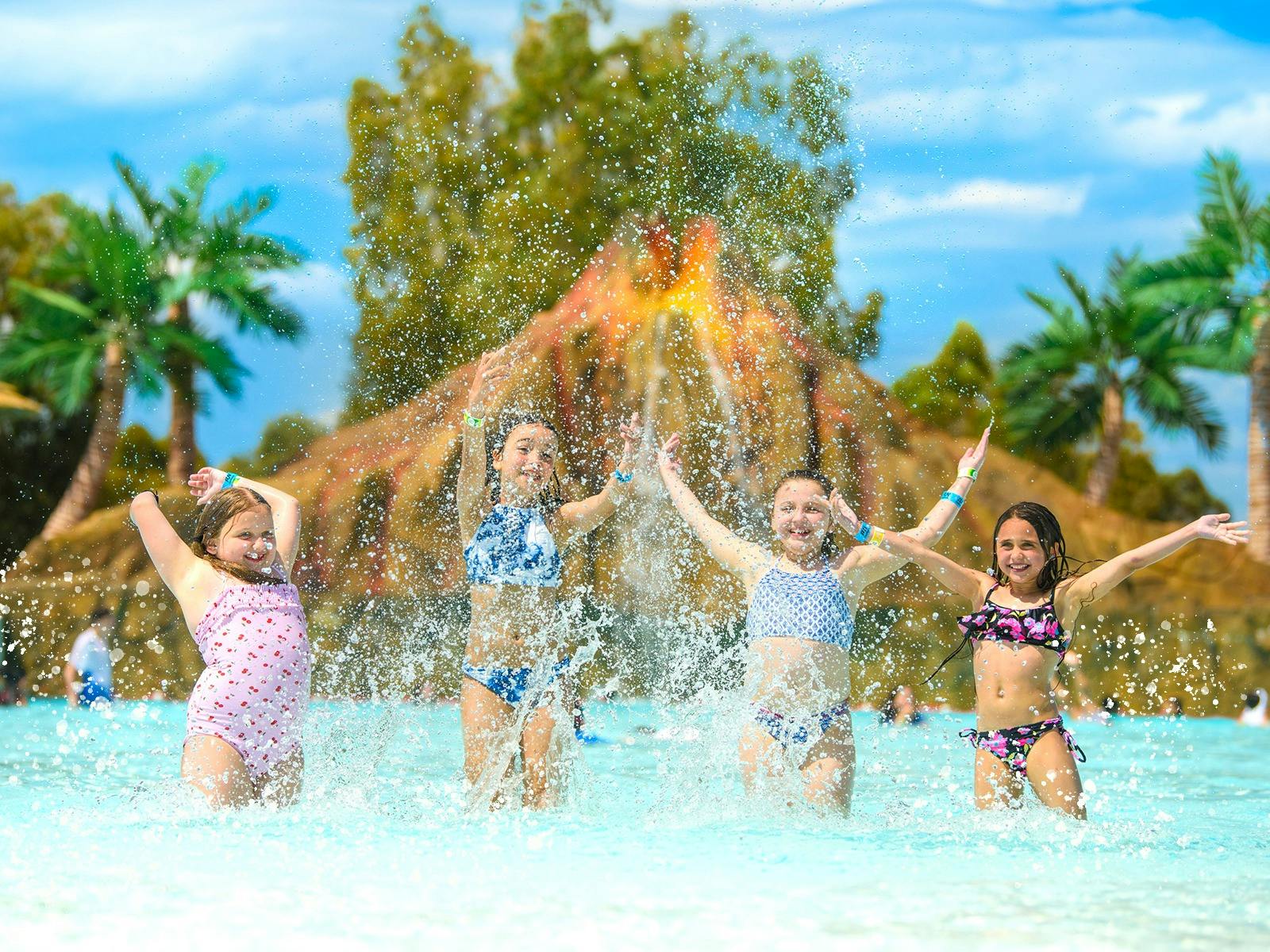 4 young people splashing in the water having fun with their friends in the big wave pool