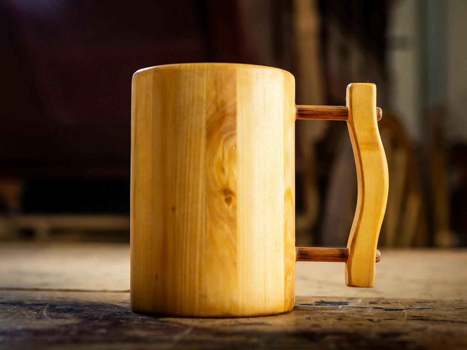 Handcrafted wooden tankard with handle displayed on table. Handcrafted wooden tankard with handle displayed on table.