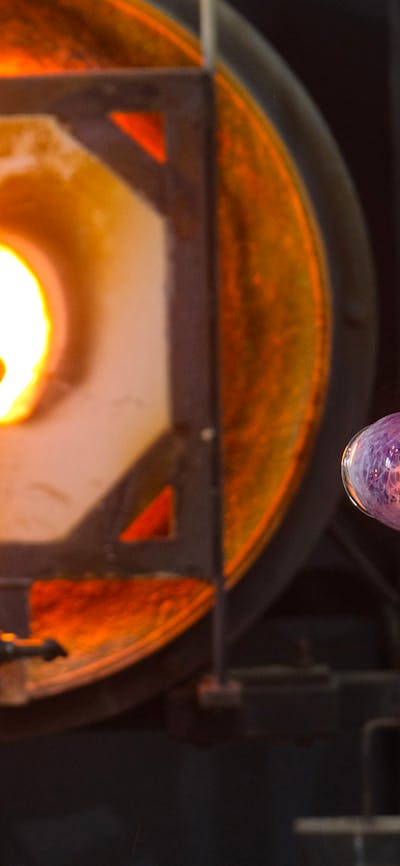 Blown glass tumbler on glass blowing pipe in the Hotshop