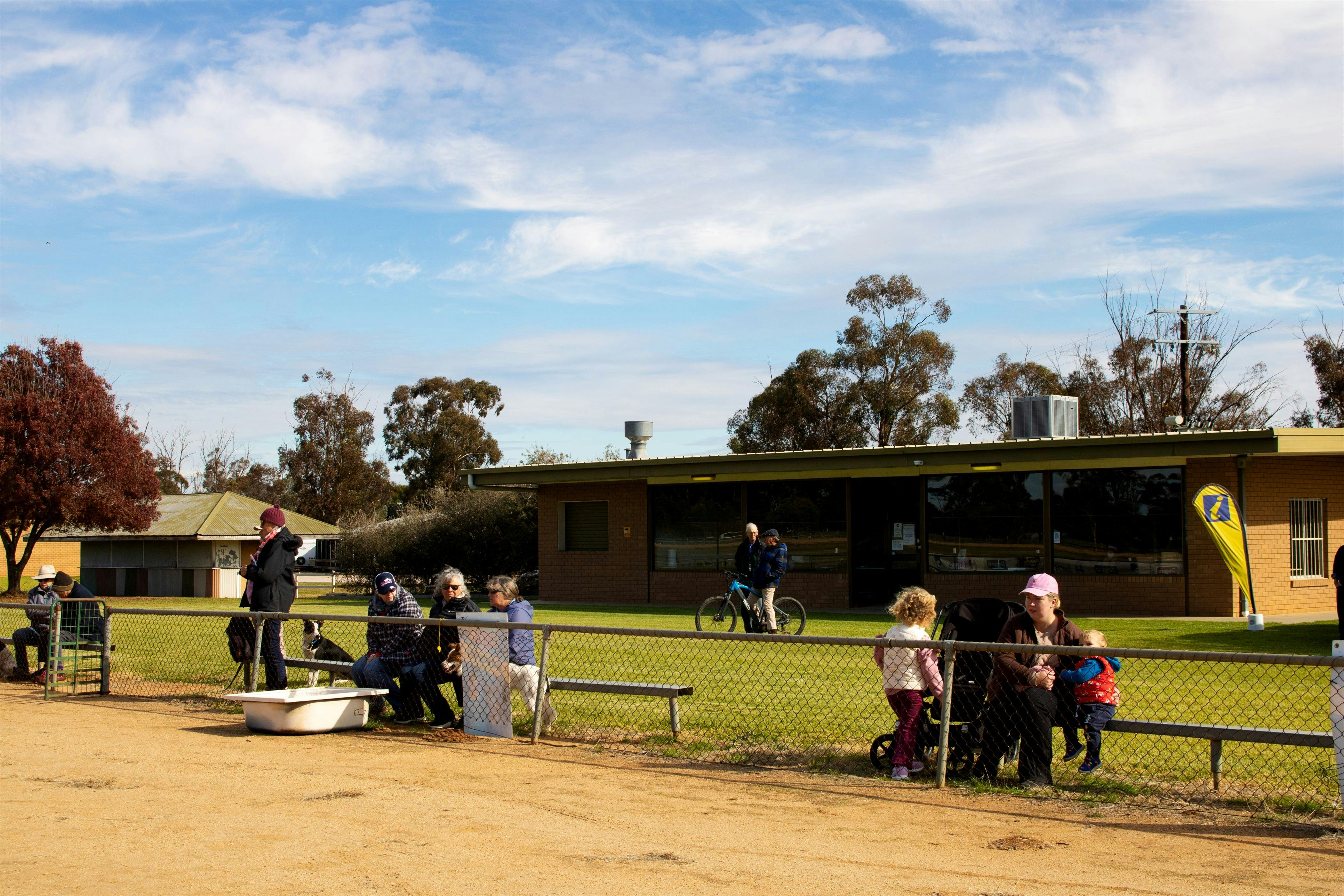 Spectators sitting along a fence, watching the action behind the camera