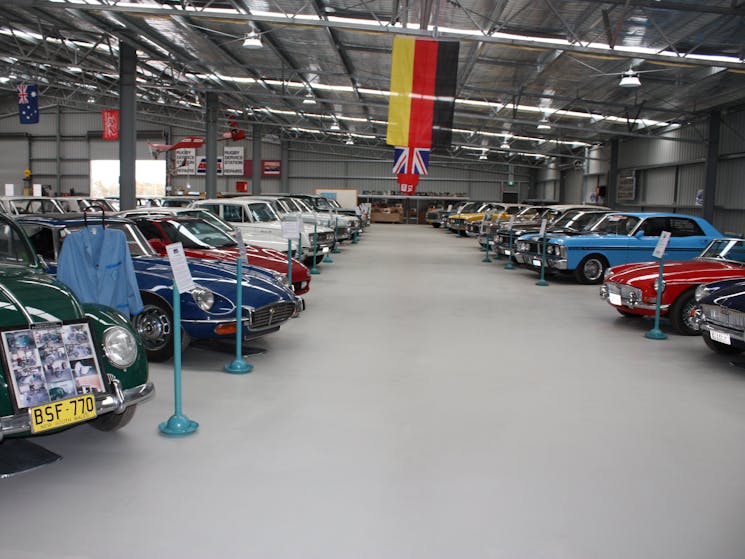 Two rows of Antique Motor Cars lined up inside a shed