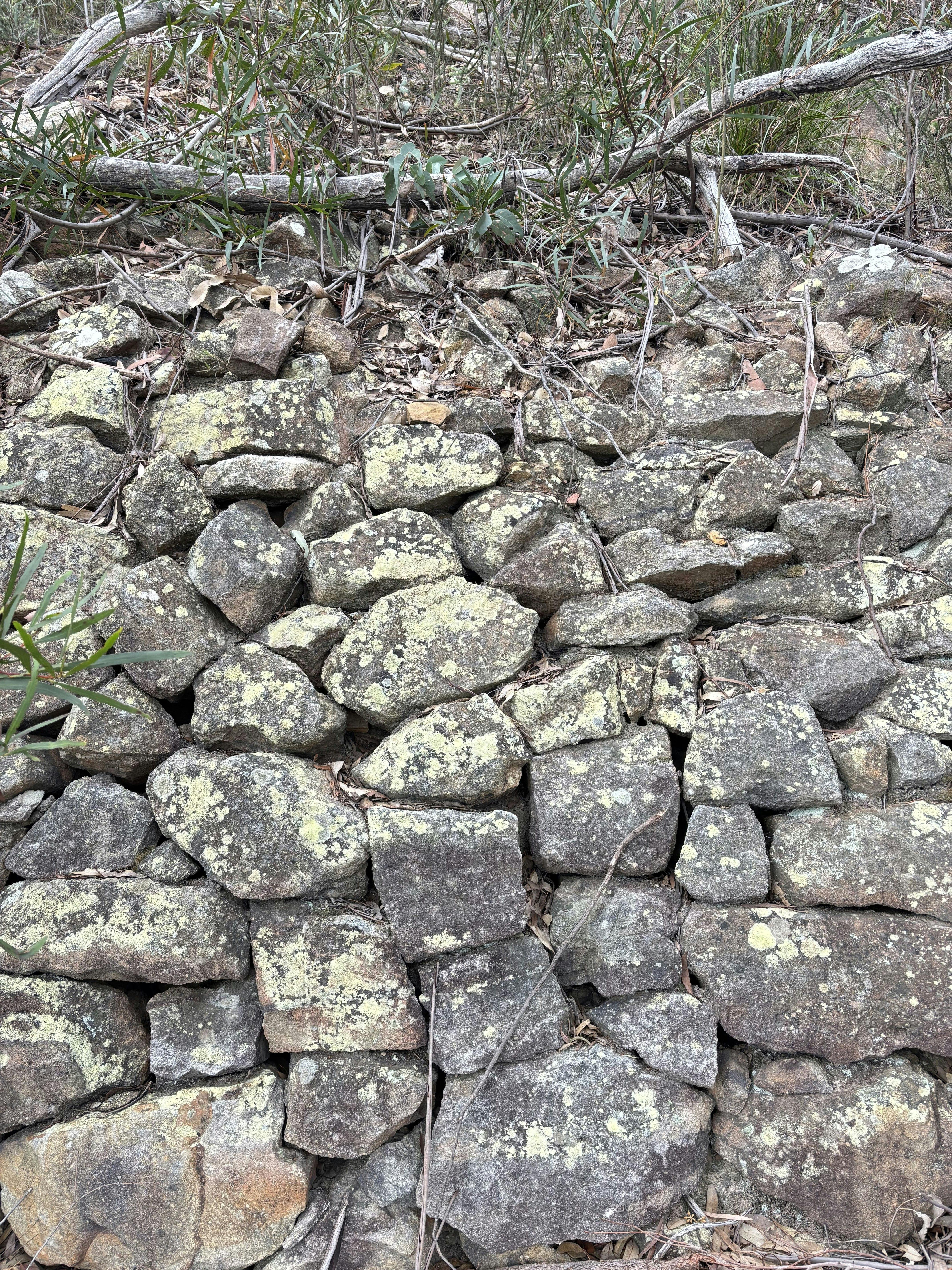A sandstone wall constructed out of hundreds of rocks lining the edge of the railway.