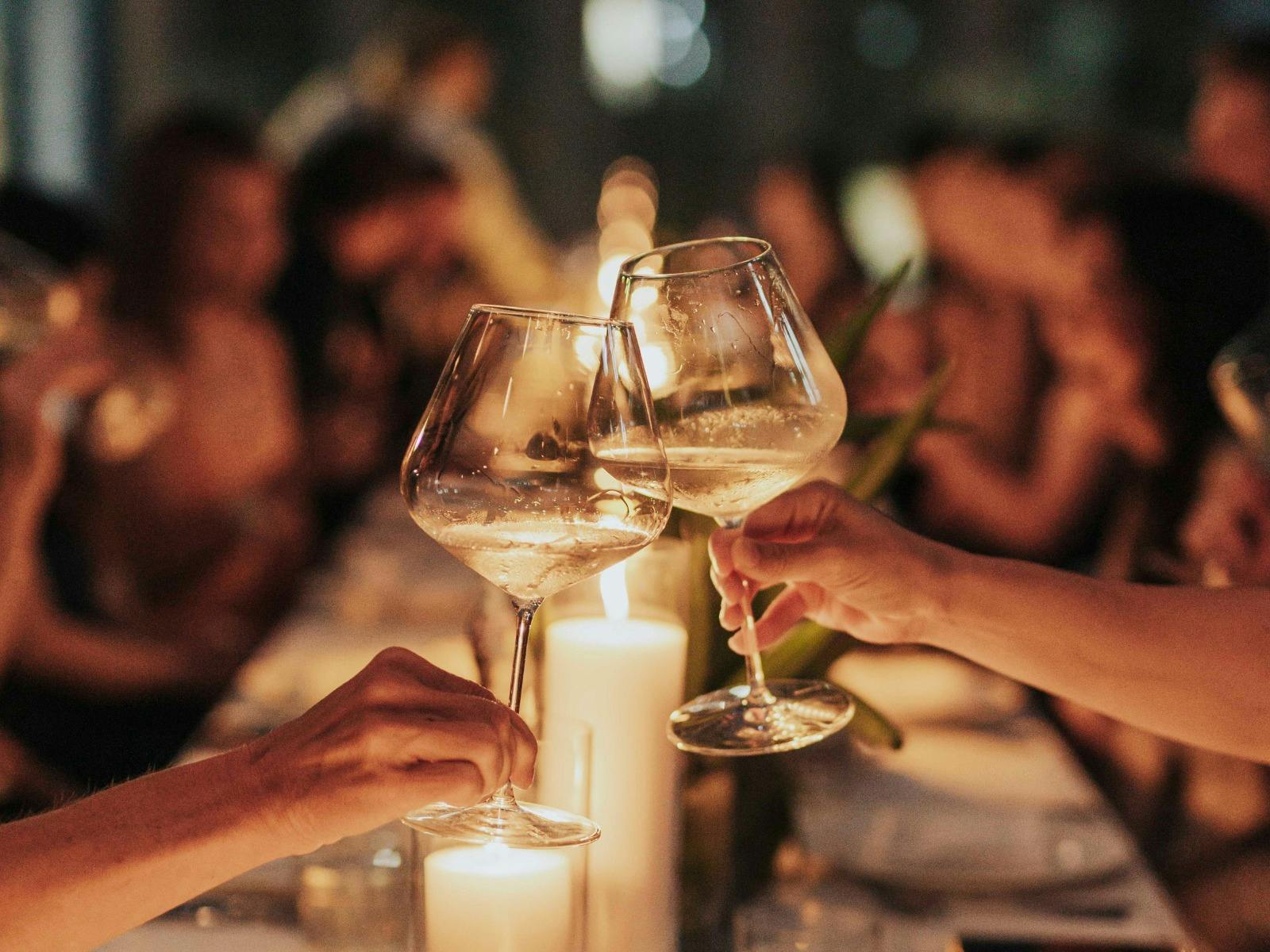 A table of people enjoy dinner on the rooftop terrace, two people cheers their wine glasses