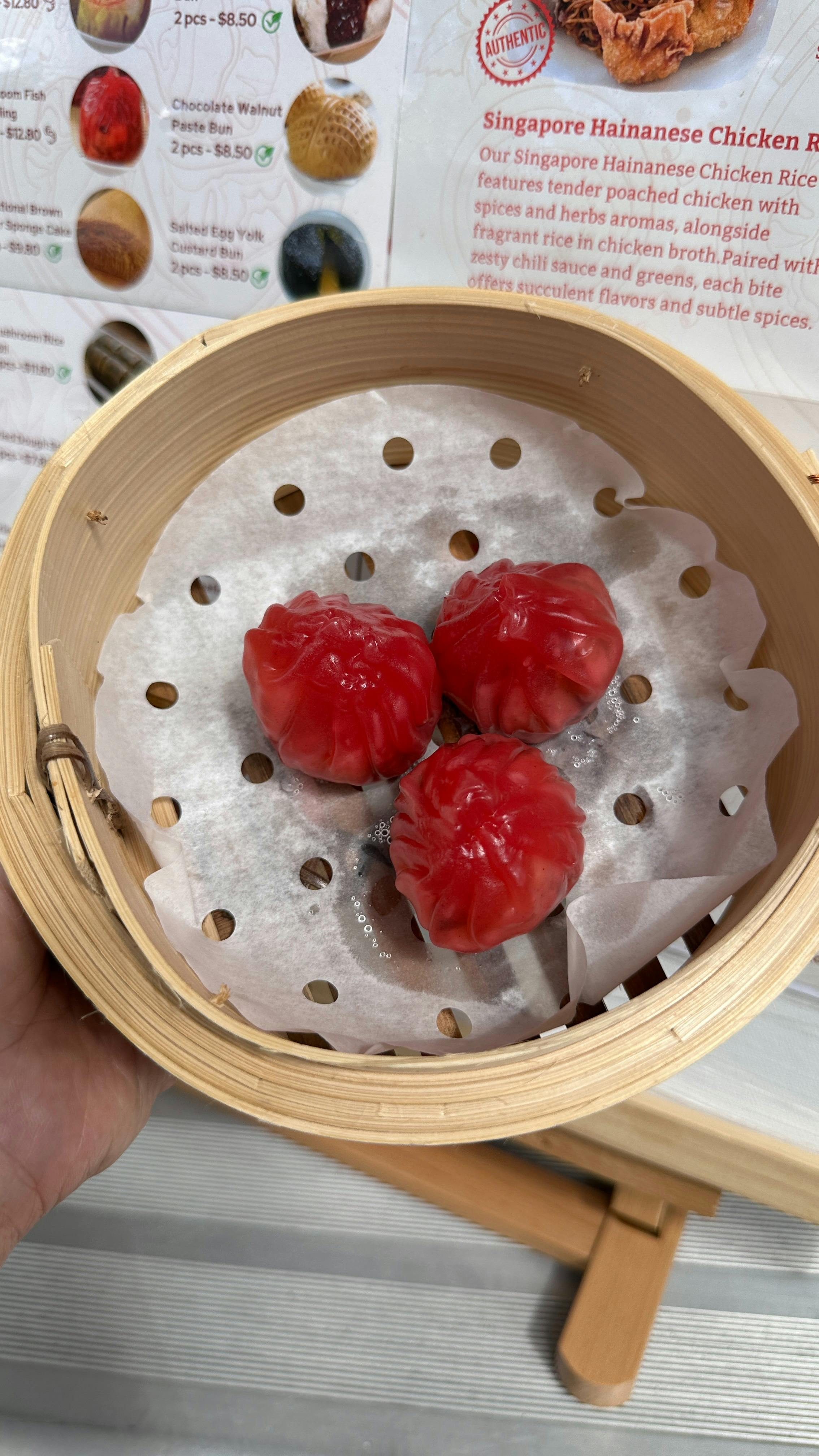 Steamed mushroom fish dumplings in bamboo steamer, glossy red skin with juicy filling.