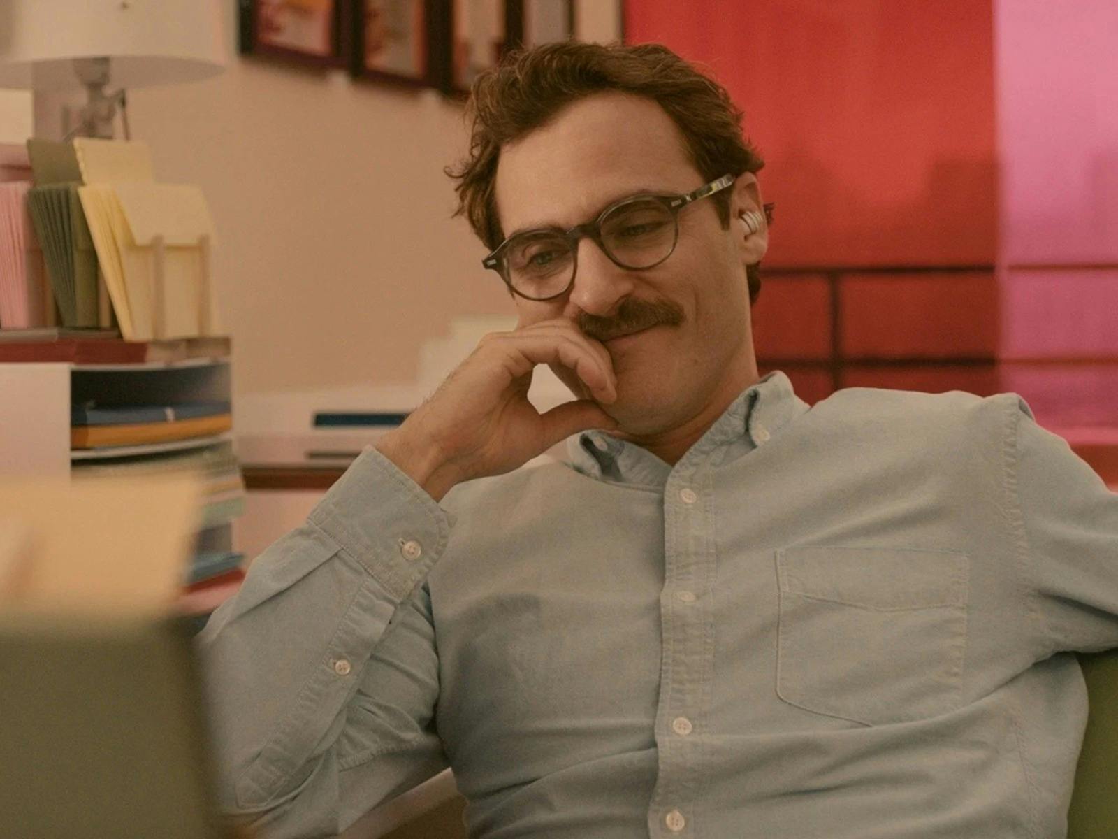 Man with moustache and glasses looking content smiling and looking down