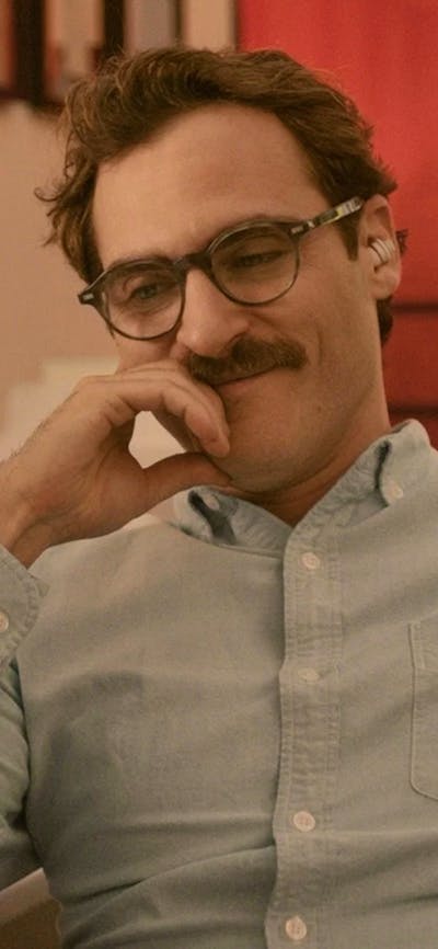 Man with moustache and glasses looking content smiling and looking down