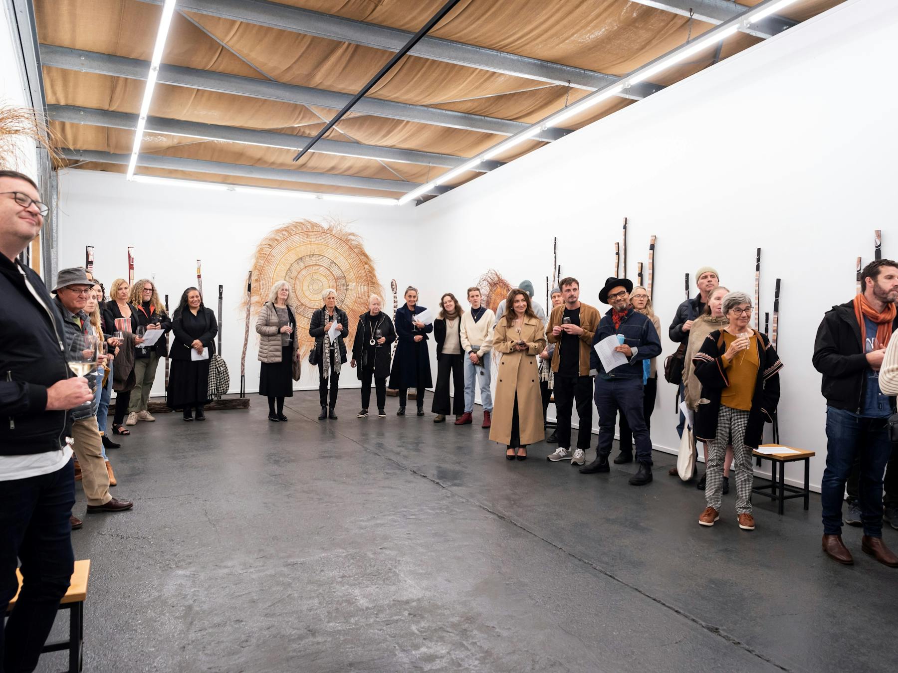 whote room with people standing along the walls and indigenous artwork on the walls