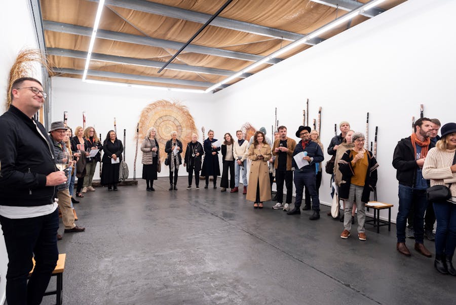 whote room with people standing along the walls and indigenous artwork on the walls