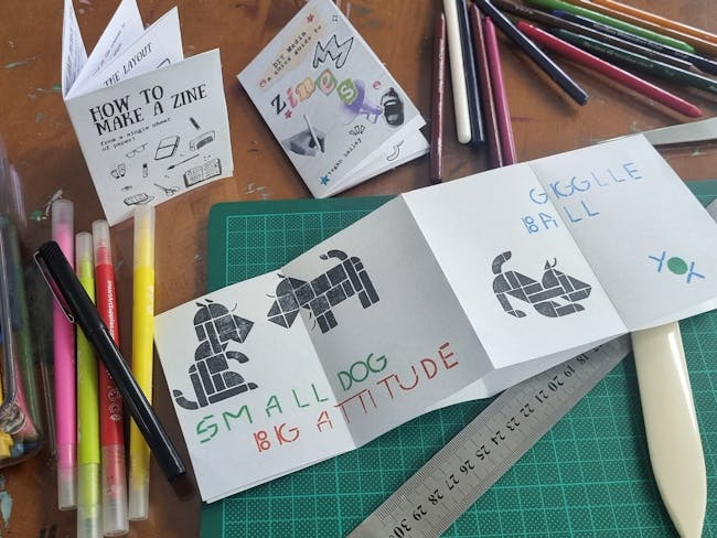 pencils, scissors, paper being folded into miniature story zines