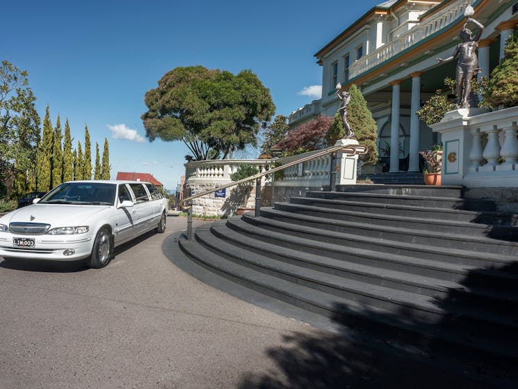 White stretch limousine at the base of steps with historic hotel in the background