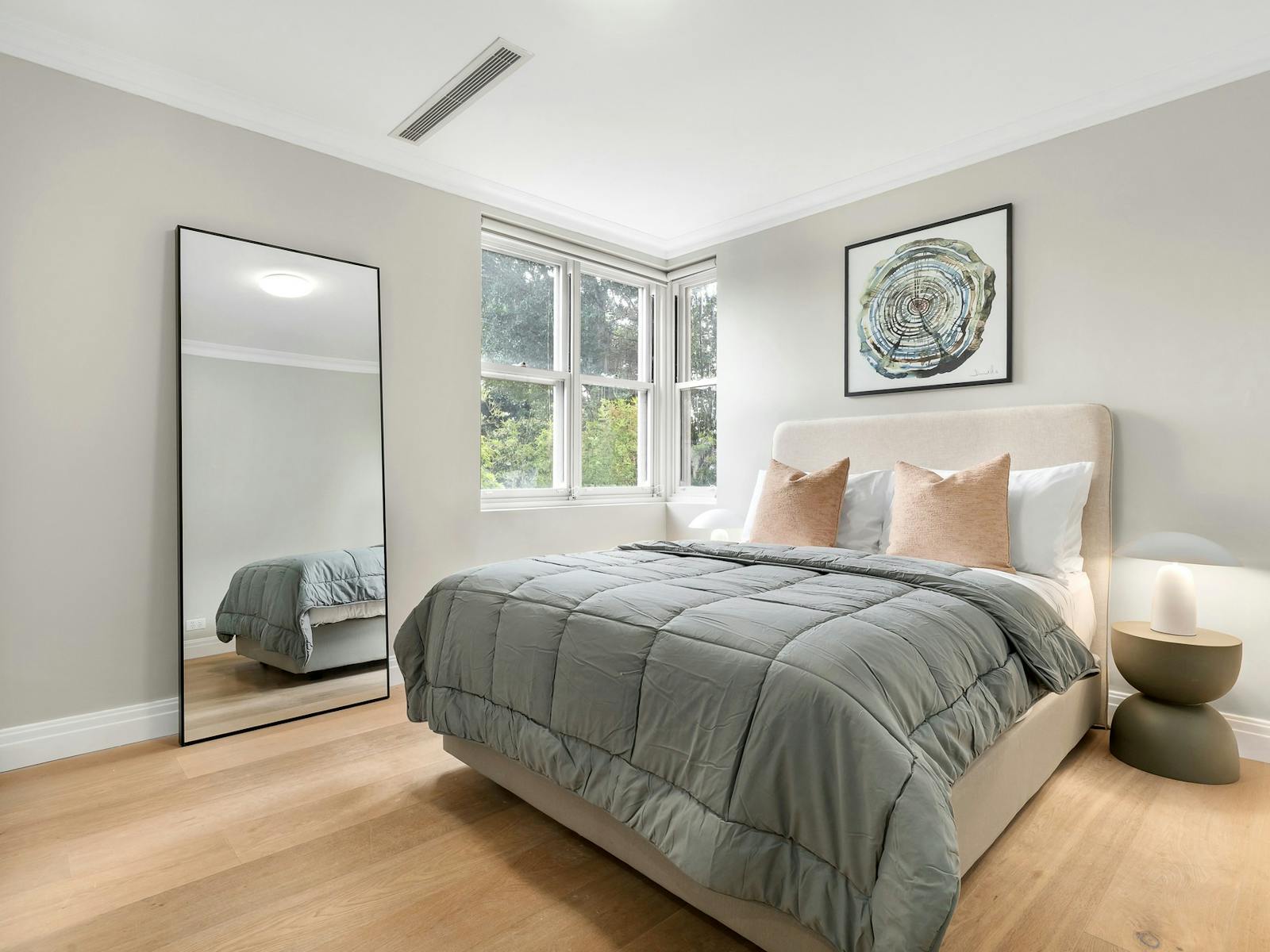 Modern, spacious bedroom with large window and full length mirror, queen sized bed and side tables.