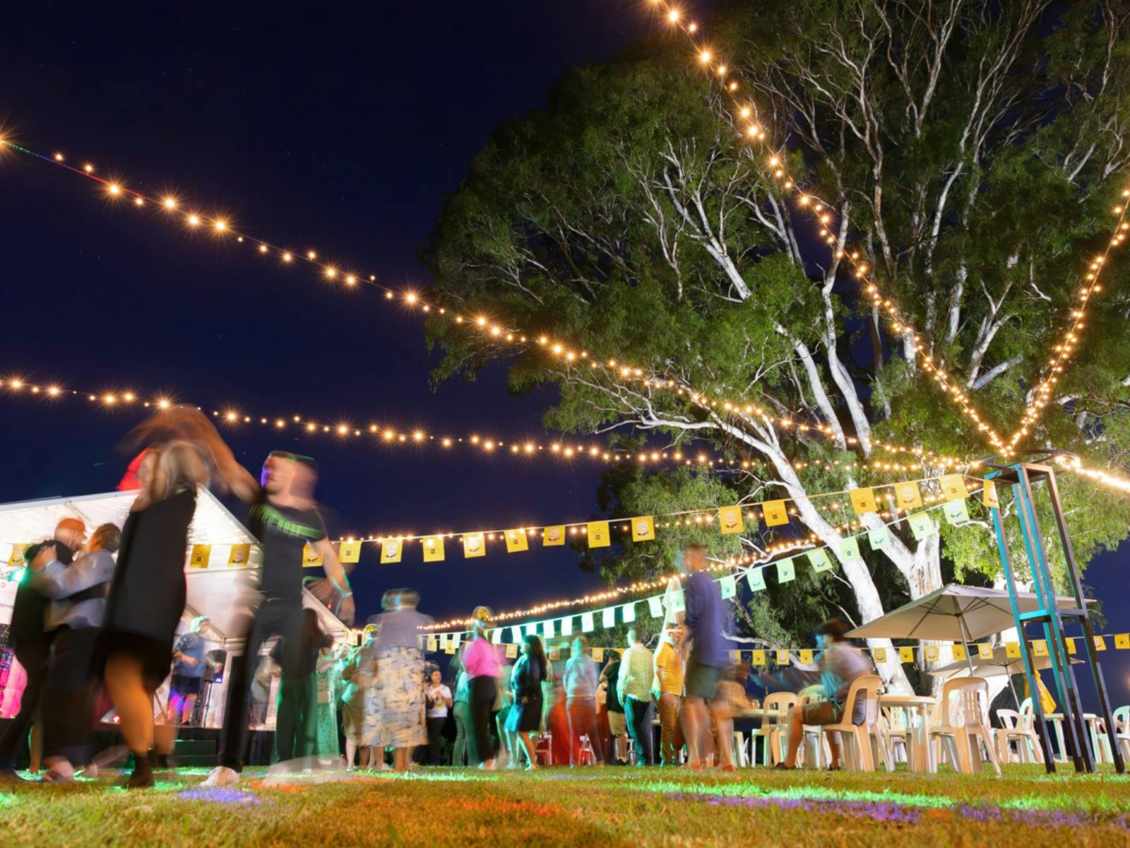 Group of people dancing under fairy lights and bunting at dal zotto prosecco festival