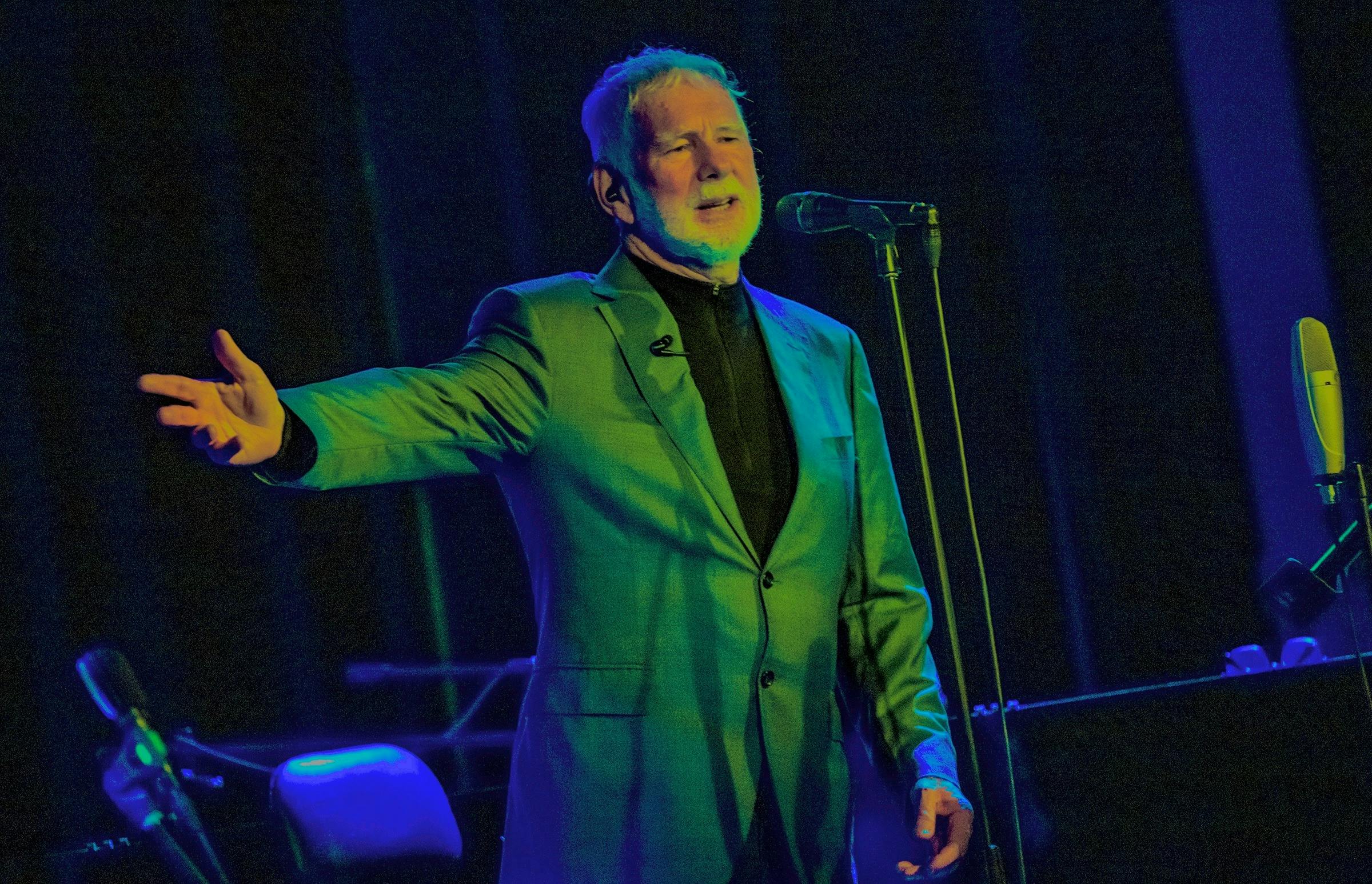 Vince Jones in Green jacket with arm extended singing into microphone