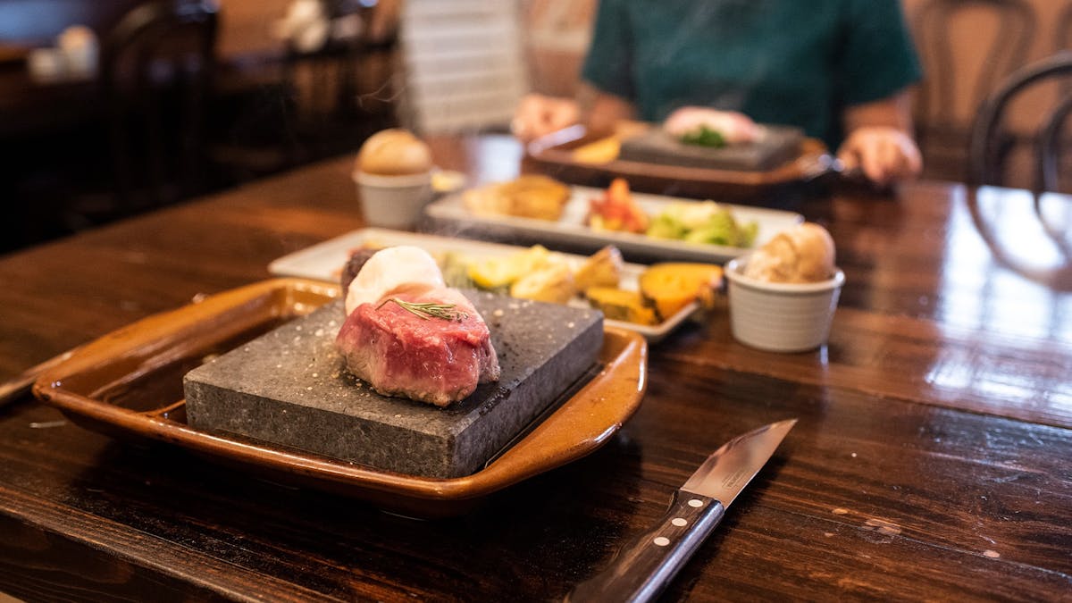 A selection of meats cooking on hot stone grills