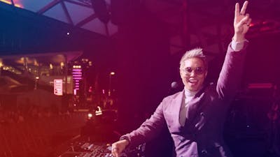 Andy Trieu doing a live DJ set  on stage doing a peace sign