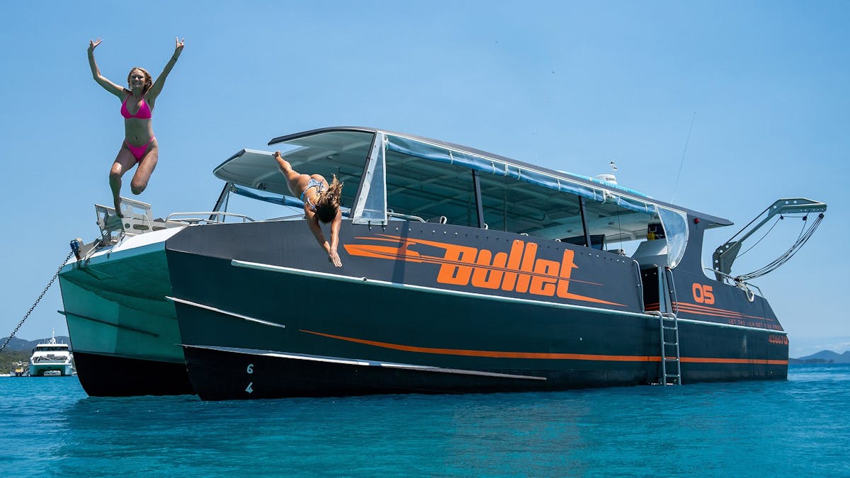 Travellers jumping from Whitsunday Bullet speedboat into clear turquoise waters