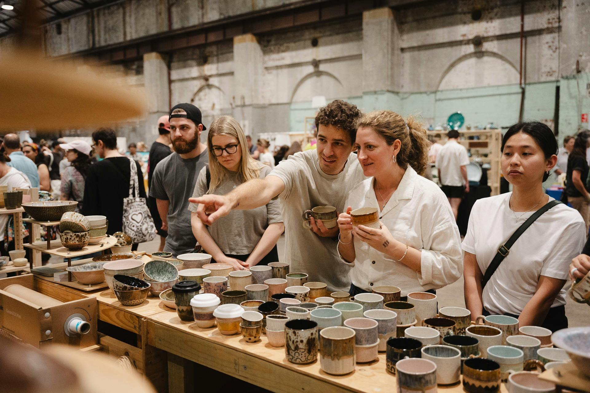A couple browse and point to unique one-off mugs by Public Holiday