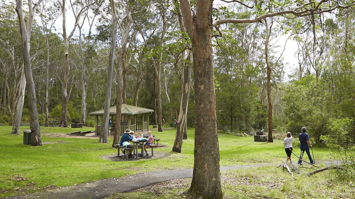 Family sitting at a picnic table in a picnic area.