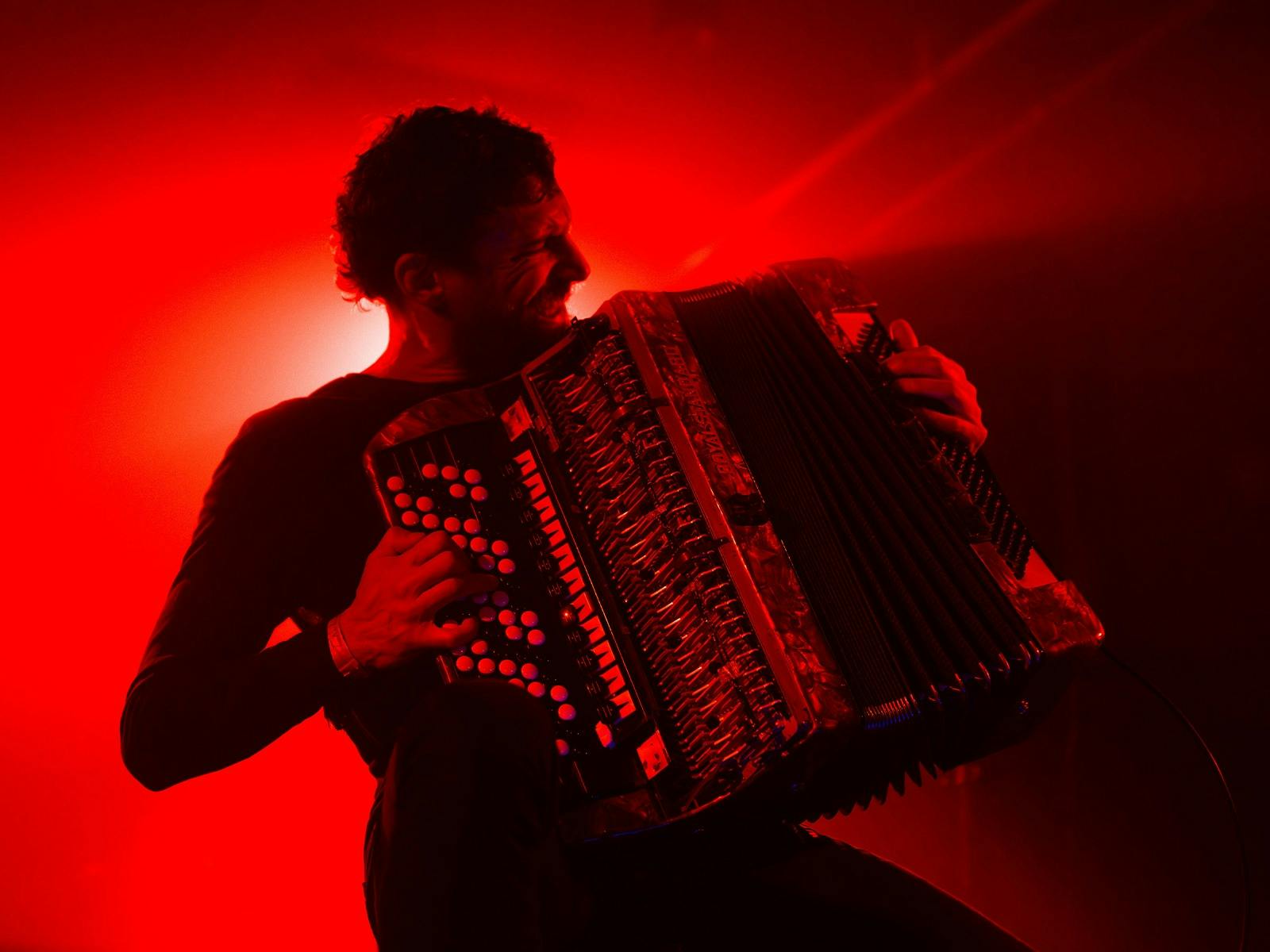 Yegor Zabelov playing the accordion with red lighting in background