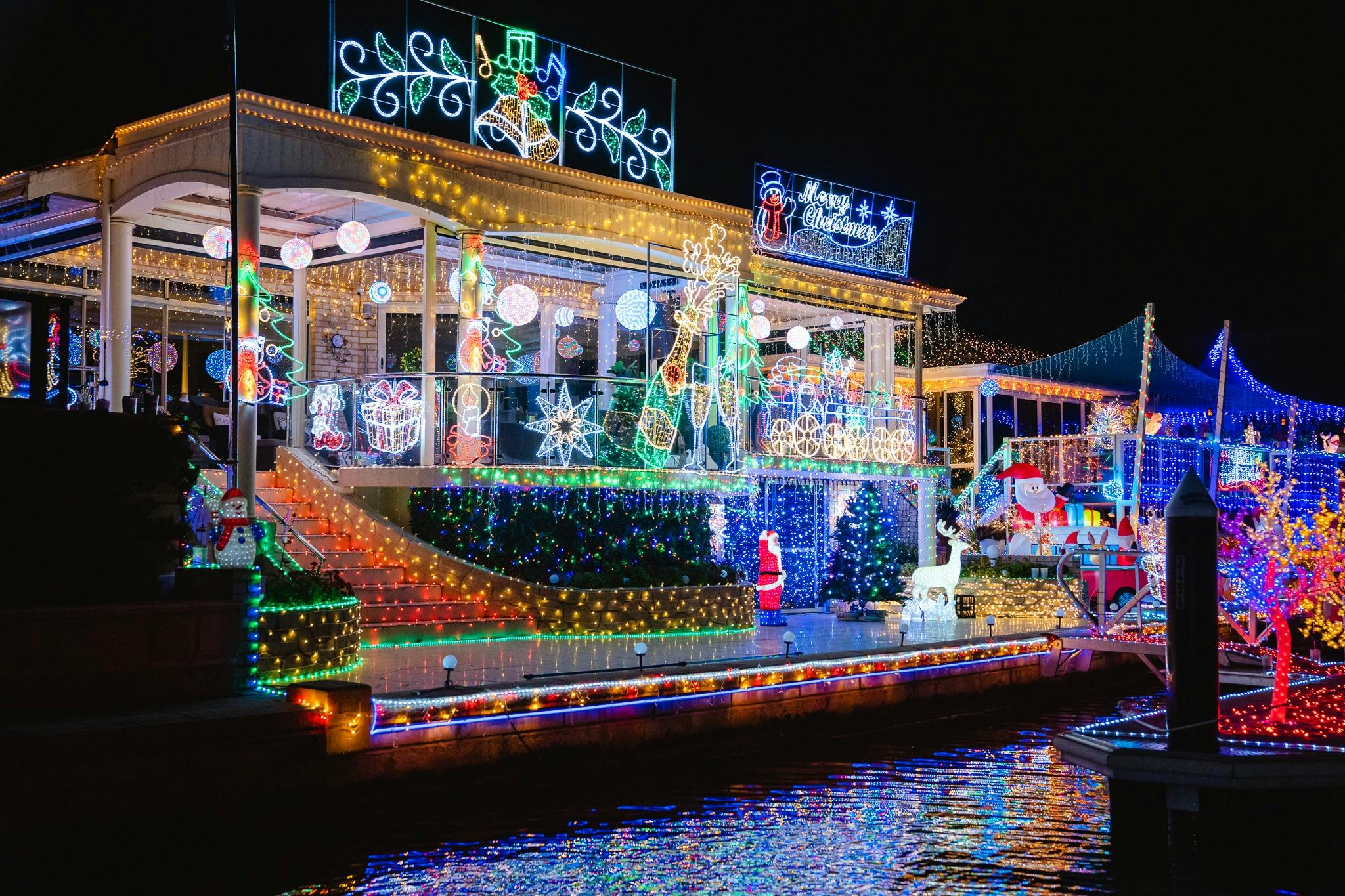 Waterfront mansion adorned with shimmering Christmas lights, reflecting beautifully on the canals.