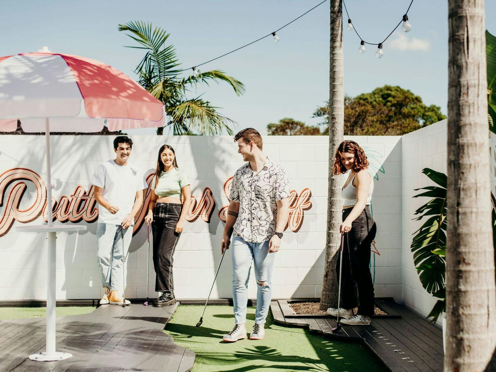 Four young people playing mini golf