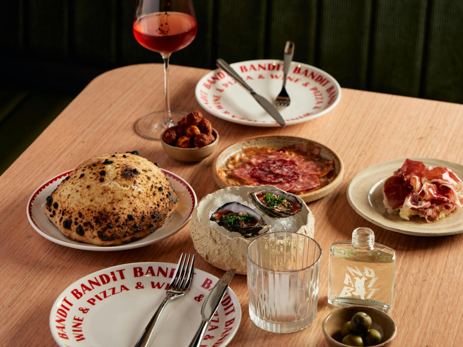 many plates of food sit on a light wooden table.