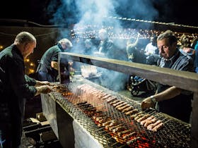 Men cooking Greek Charcoal Grill at night as part of After Dark Festival