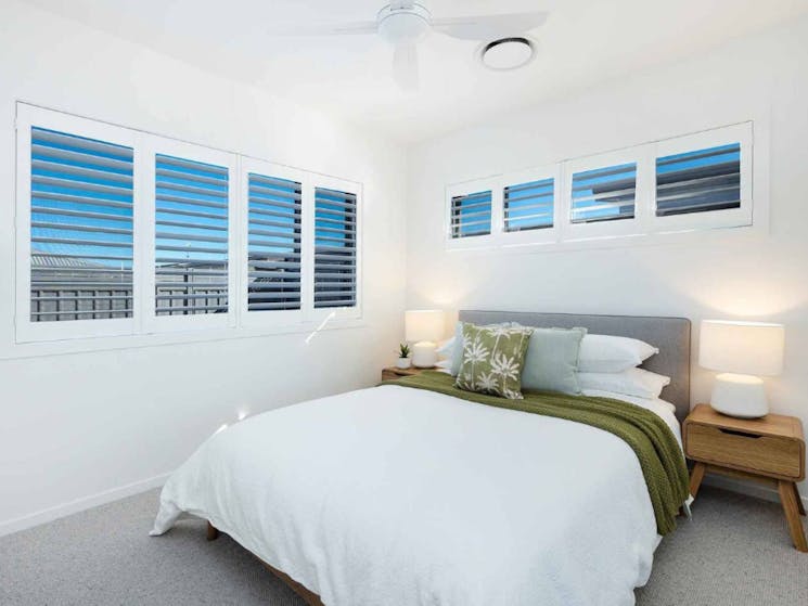 Bedroom with white shutters and ceiling fan